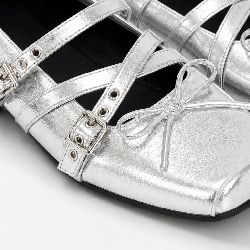 Close-up of silver Mary Jane flats showing bow buckle strap and finish detail